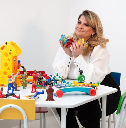 Psicóloga Patrícia Lorena em frente a uma mesa com brinquedos da Lego