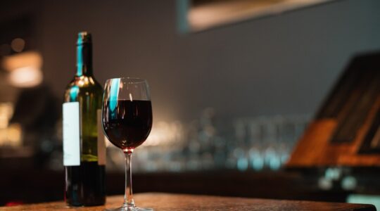 copo-de-vinho-tinto-e-garrafa-no-balcao-de-bar_107420-65845