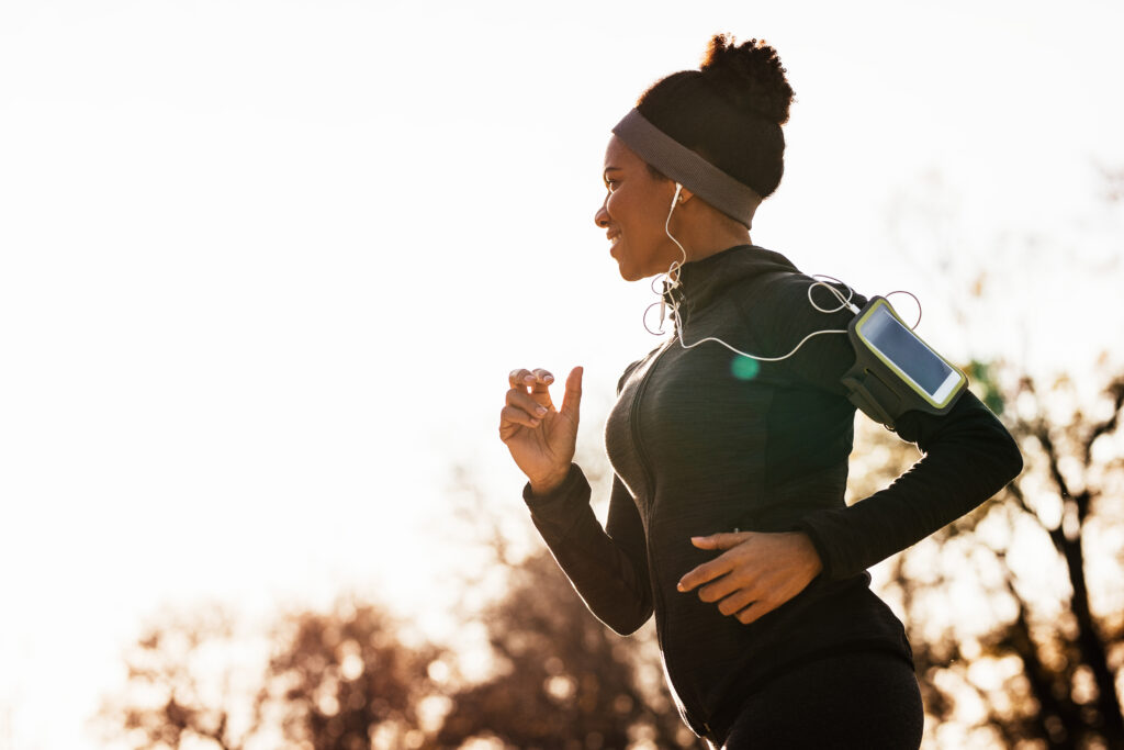 Happy black sportswoman jogging while exercising in nature.