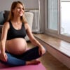 Pregnant Woman Wearing Fitness Clothing On Exercise Mat At Home Doing Yoga