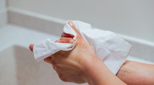 Close-up of woman using wet wipe and cleaning her hands.