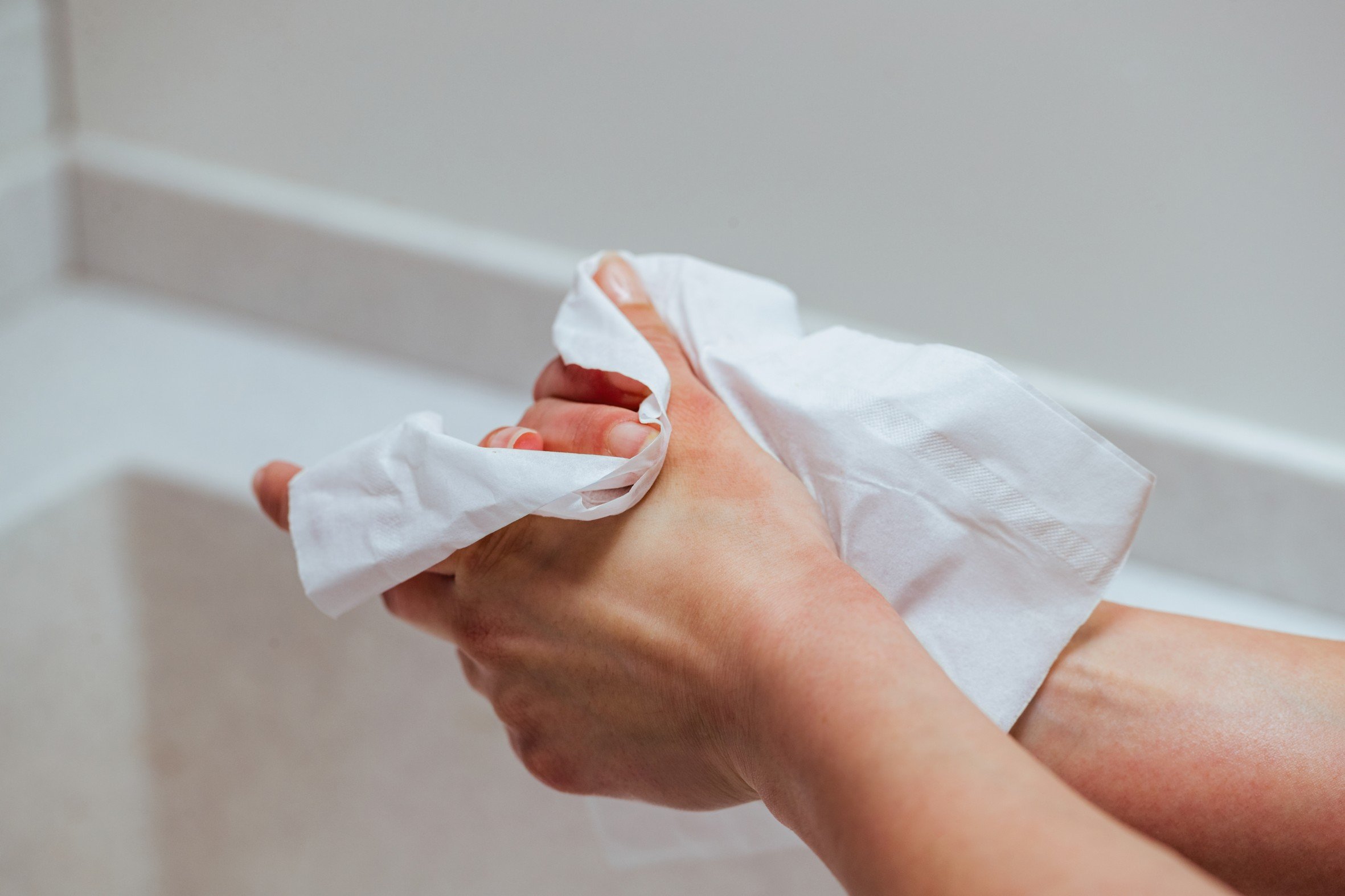 Close-up of woman using wet wipe and cleaning her hands.