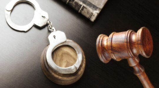 Judges Gavel, Handcuffs And Old Book On The Black Table