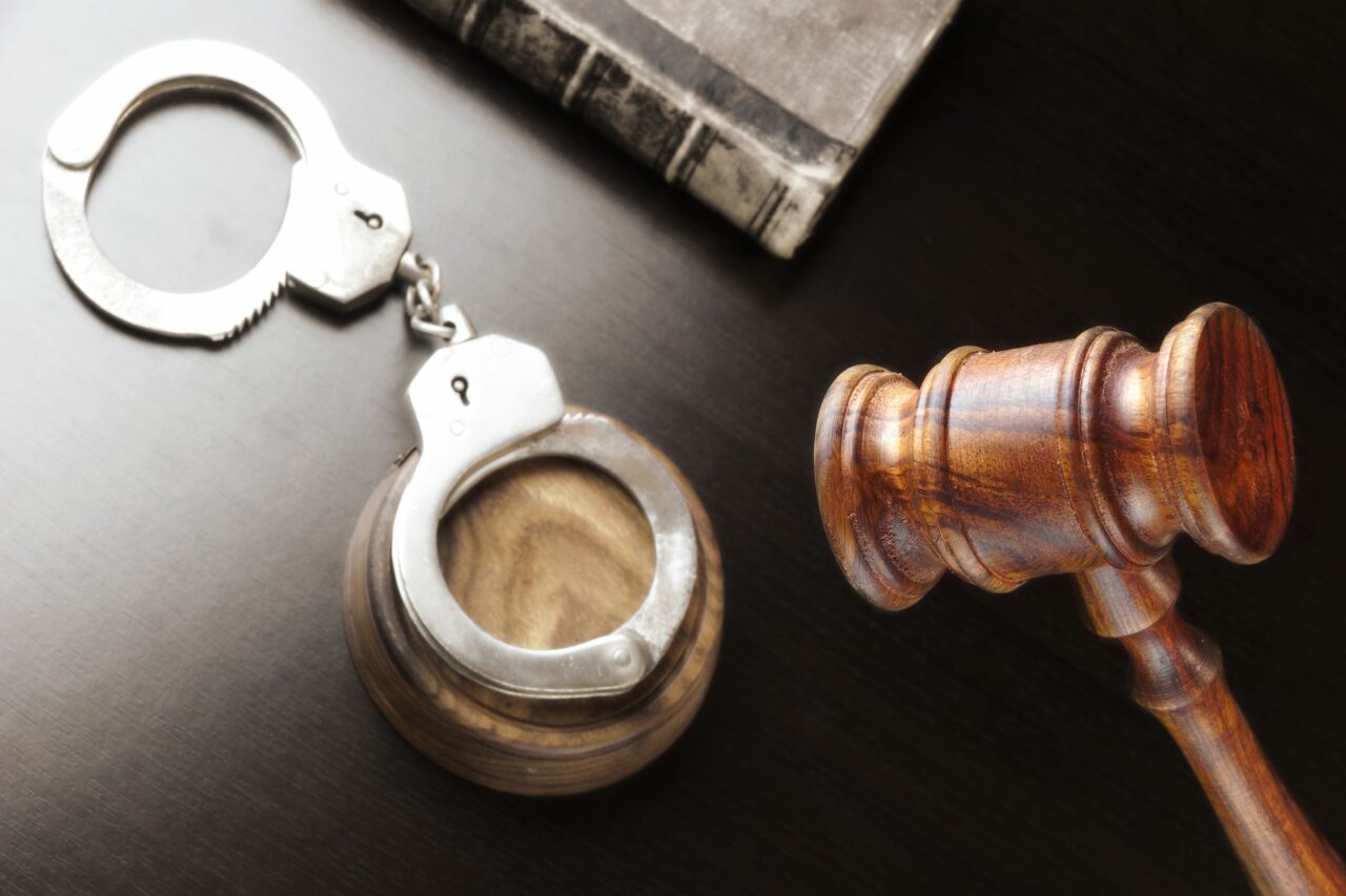 Judges Gavel, Handcuffs And Old Book On The Black Table