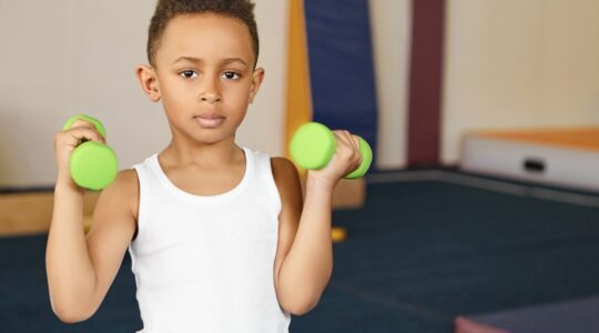Cute boy athlete of African appearance doing physical exercises