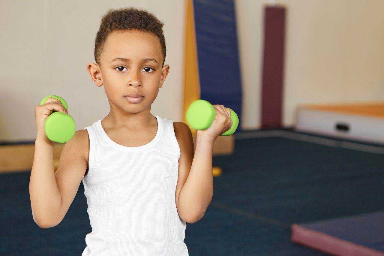 Cute boy athlete of African appearance doing physical exercises