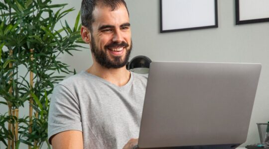 homem-sorridente-trabalhando-em-casa-em-um-laptop_23-2148806669
