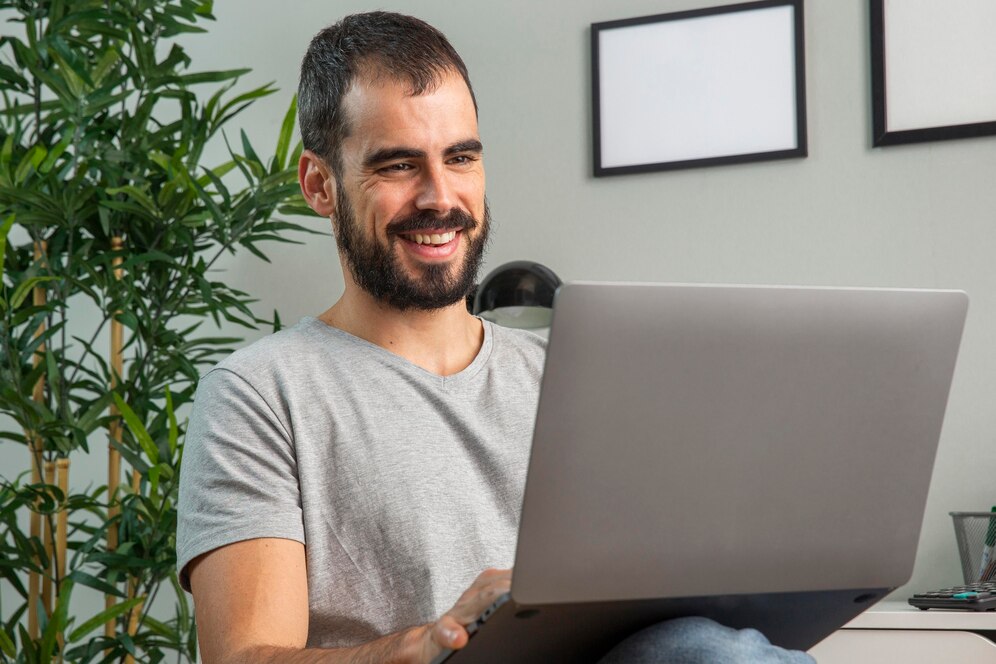 homem-sorridente-trabalhando-em-casa-em-um-laptop_23-2148806669