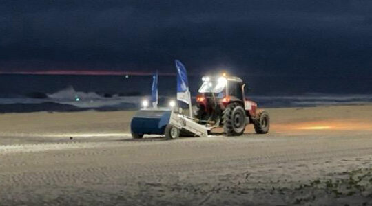 Máquina saneadora inicia limpeza da areia da praia
