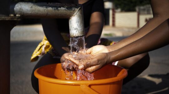 african-woman-pouring-water-recipient-outdoors