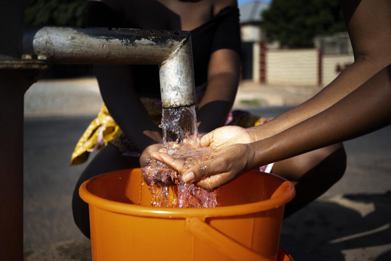 african-woman-pouring-water-recipient-outdoors