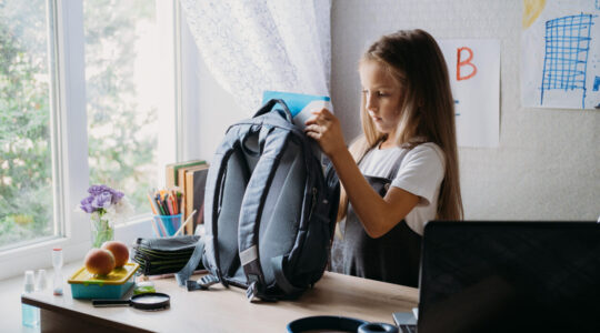 Back to school, schoolchildren hygiene, safety precautions after coronavirus. The schoolgirl is going to school and washing her hands with sanitizer