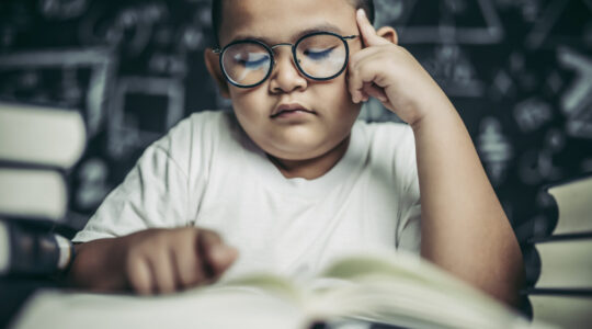 Boys with glasses write books and think in the classroom