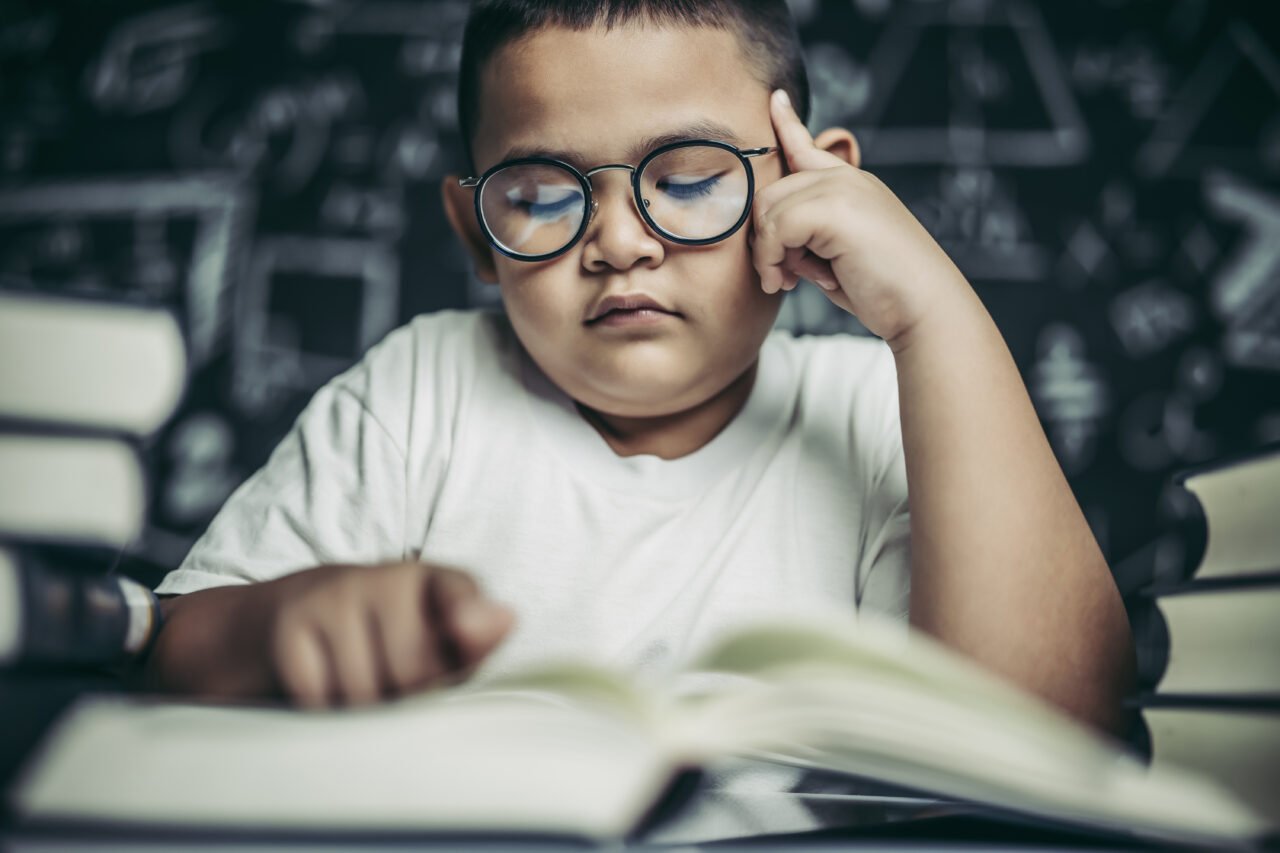 Boys with glasses write books and think in the classroom