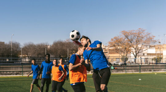 striker heads a football against a defender’s opposition