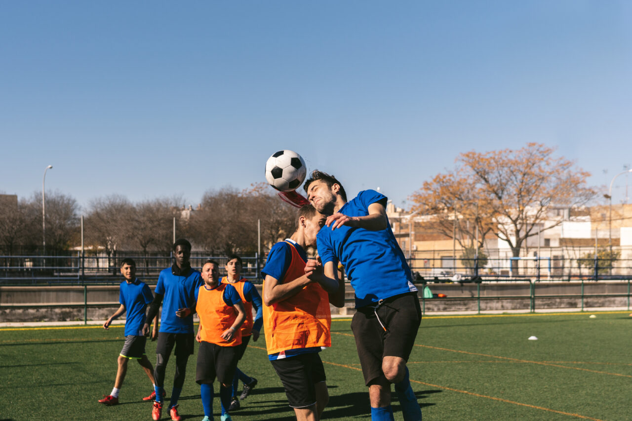 striker heads a football against a defender’s opposition