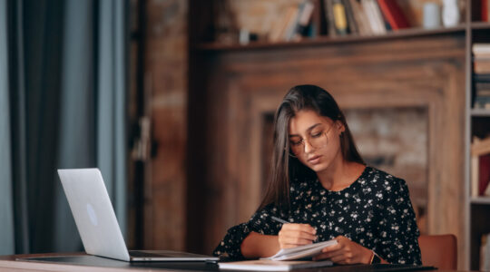Beautiful business woman writing something in notebook.