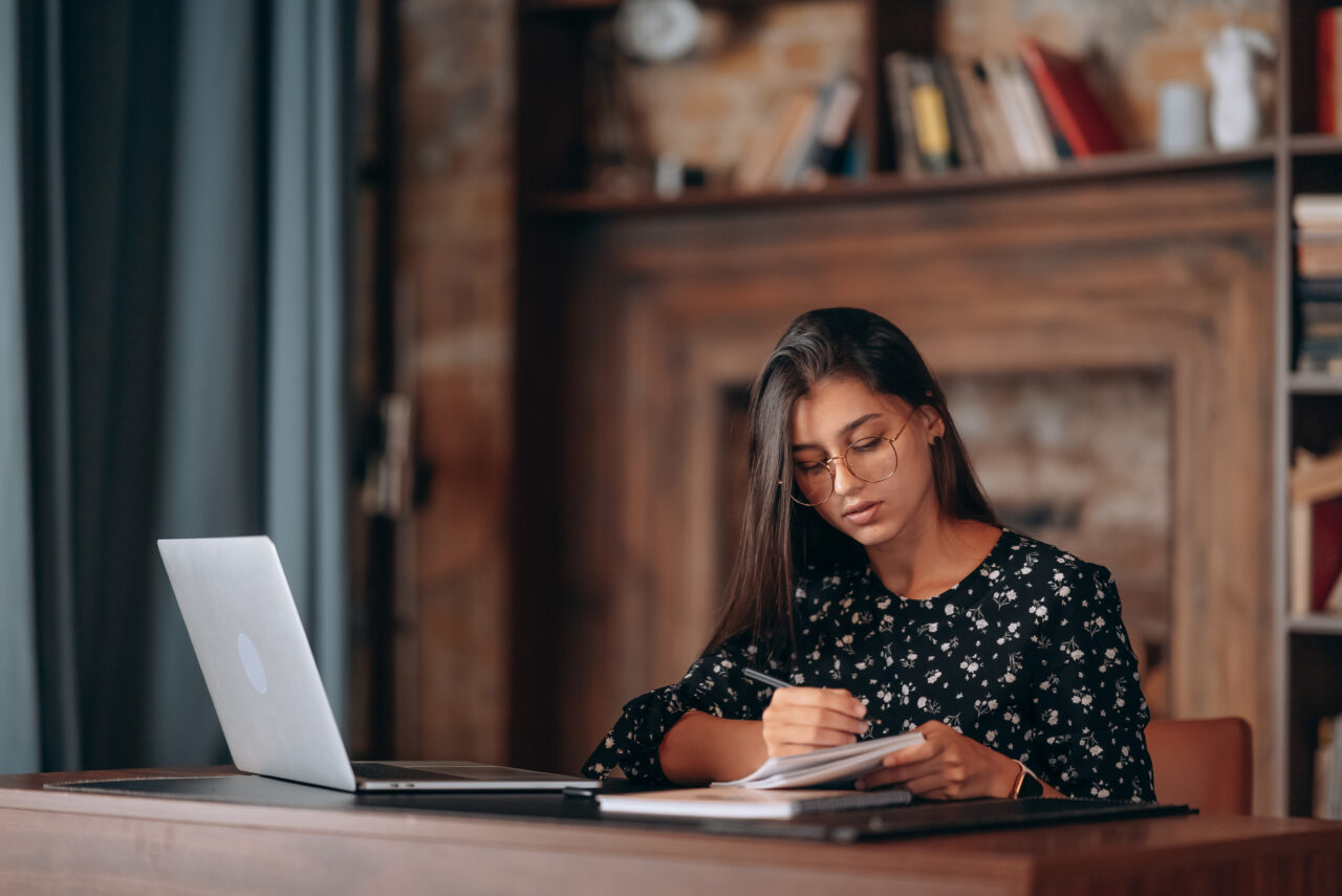 Beautiful business woman writing something in notebook.