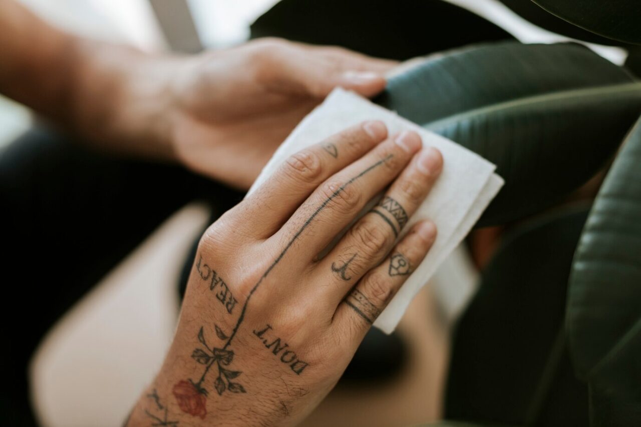 mao-tatuada-limpando-a-folha-da-planta-de-casa_53876-129315