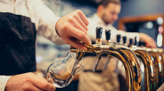 Two handsome bartenders poring beer at pub