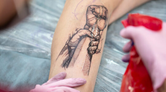 Tattoo master professional application of alcohol on the skin of clients