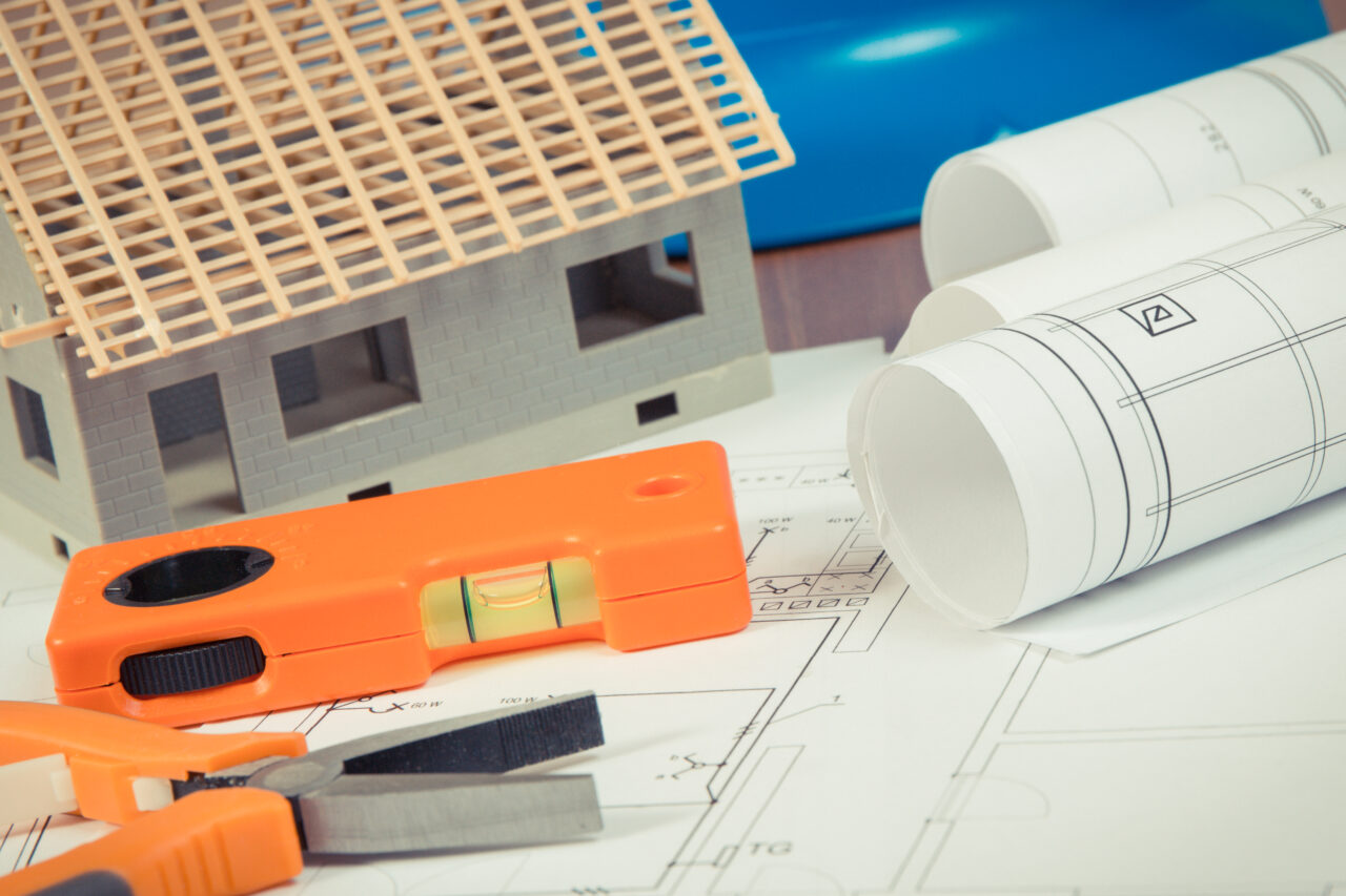 Electrical diagrams, orange work tools, blue helmet for engineer jobs and house under construction, building home concept