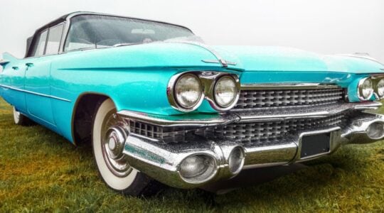 Closeup shot of a turquoise car parked on a green field