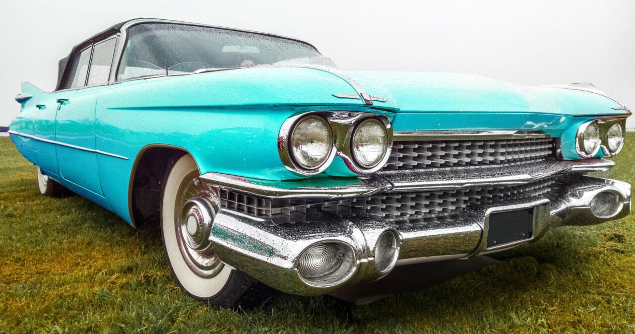 Closeup shot of a turquoise car parked on a green field