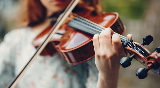 Beautiful girl in a summer park with a violin