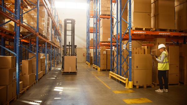 Retail Warehouse full of Shelves with Goods in Cardboard Boxes, Workers Scan and Sort Packages, Move Inventory with Pallet Trucks and Forklifts. Product Distribution Delivery Center.