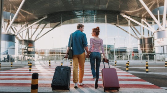 Beautiful loving couple with travel suitcases holding hands in airport