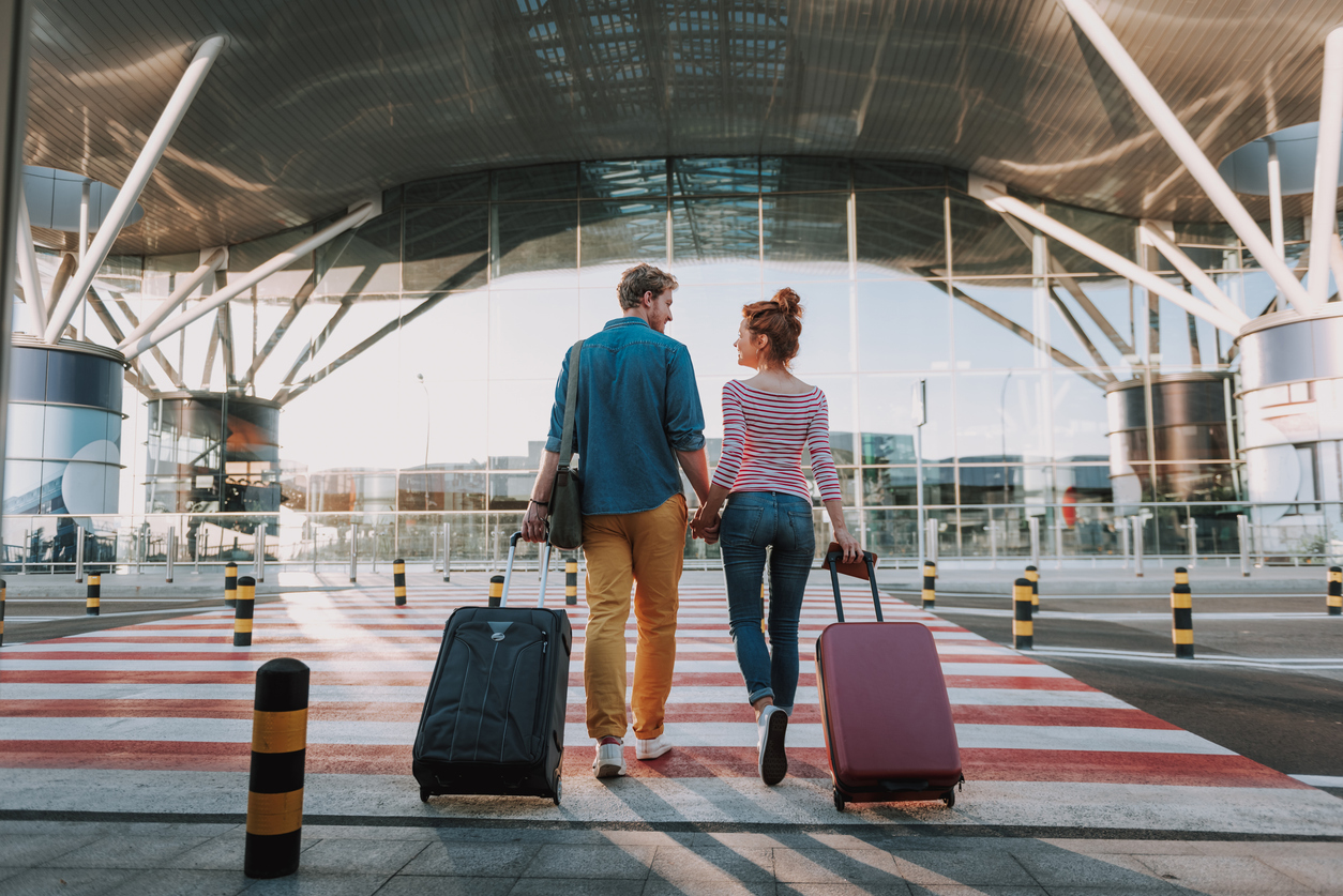 Beautiful loving couple with travel suitcases holding hands in airport