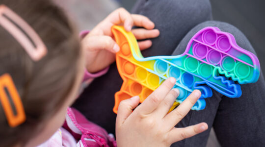 Close-up of a trendy toy pop it in the hands of a little girl.