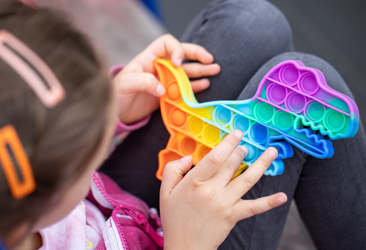 Close-up of a trendy toy pop it in the hands of a little girl.