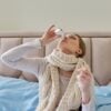 Sick woman at home in bed using nasal drops