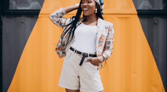 Stylish african american woman by the colored wall