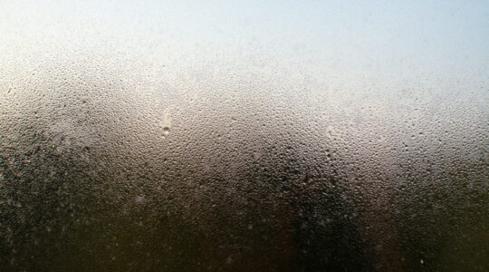 uma-foto-em-close-de-uma-janela-enevoada-com-gotas-de-agua
