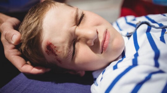 Paramedics examining injured boy on street