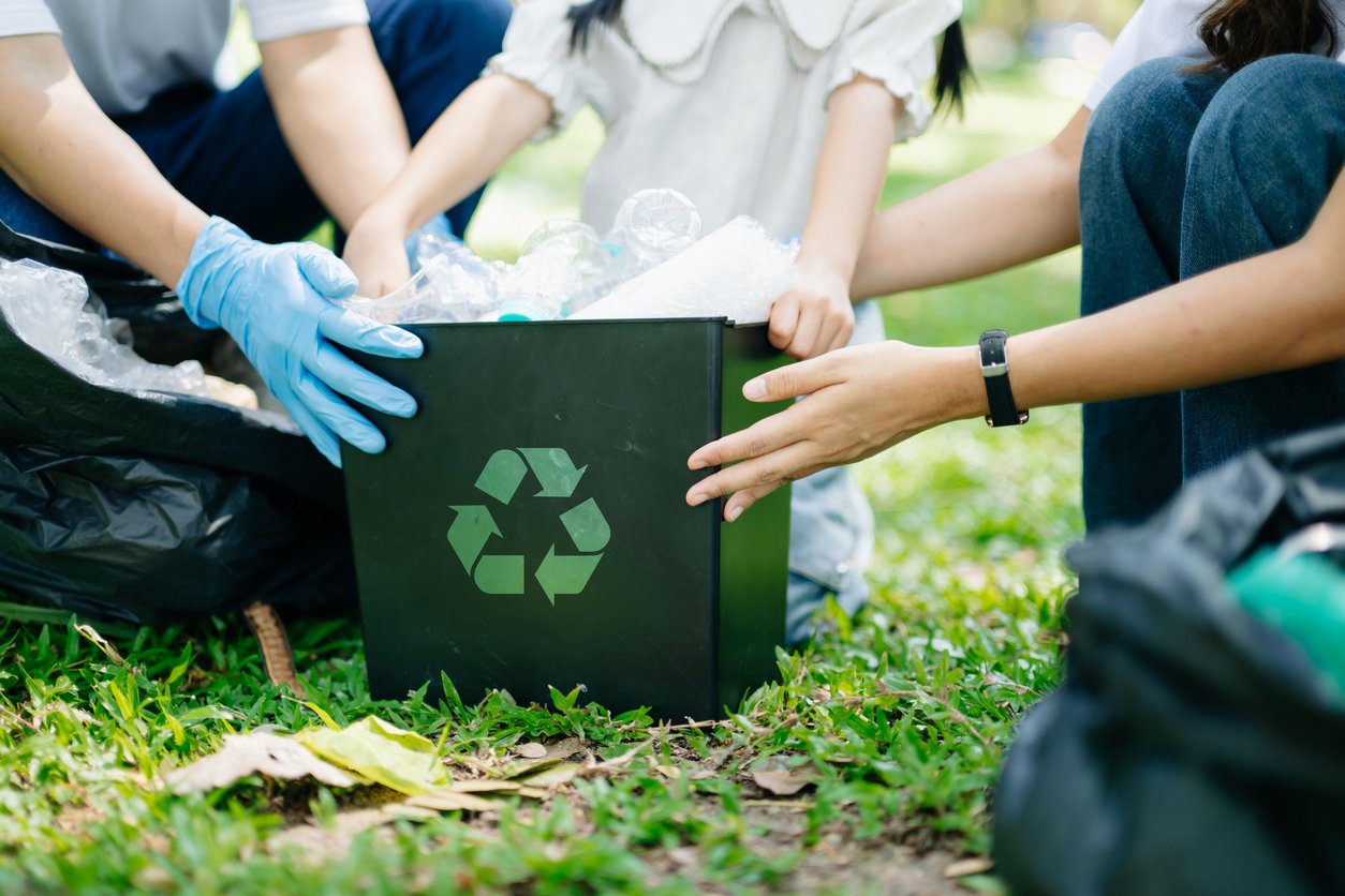 Woman’s hand picks up plastic waste for cleaning into recycle bag for cleaningat the park. Clearing, pollution, ecology