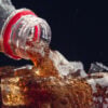 Serving a Cola from a bottle to a glass full of ice