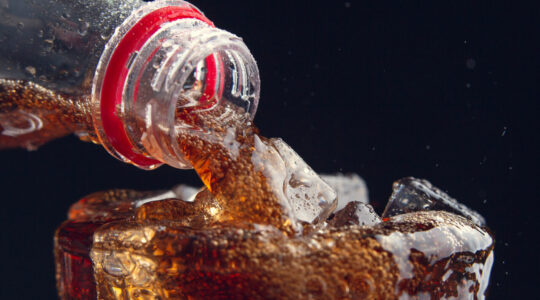 Serving a Cola from a bottle to a glass full of ice