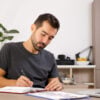 Man writing on notebook at his desk.
