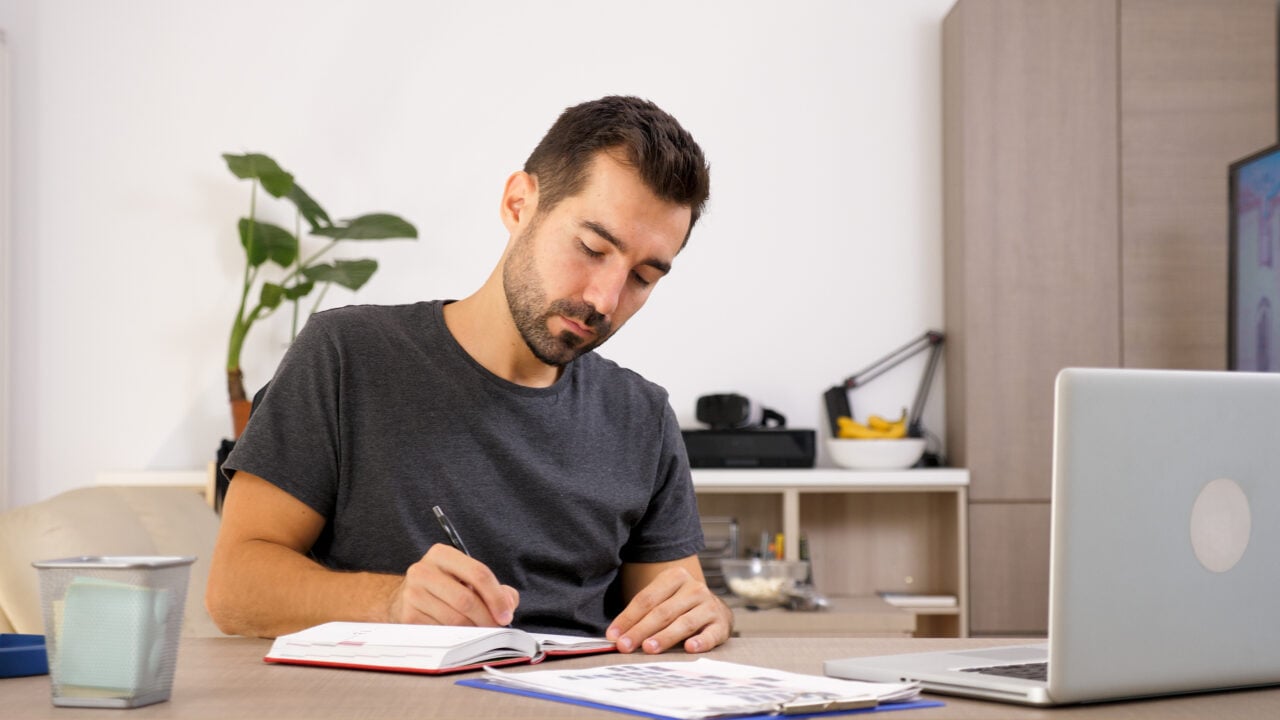 Man writing on notebook at his desk.