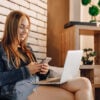 attractive girls in electronics store in lounge area on sofa with laptops and phones.
