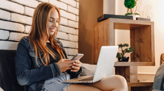attractive girls in electronics store in lounge area on sofa with laptops and phones.