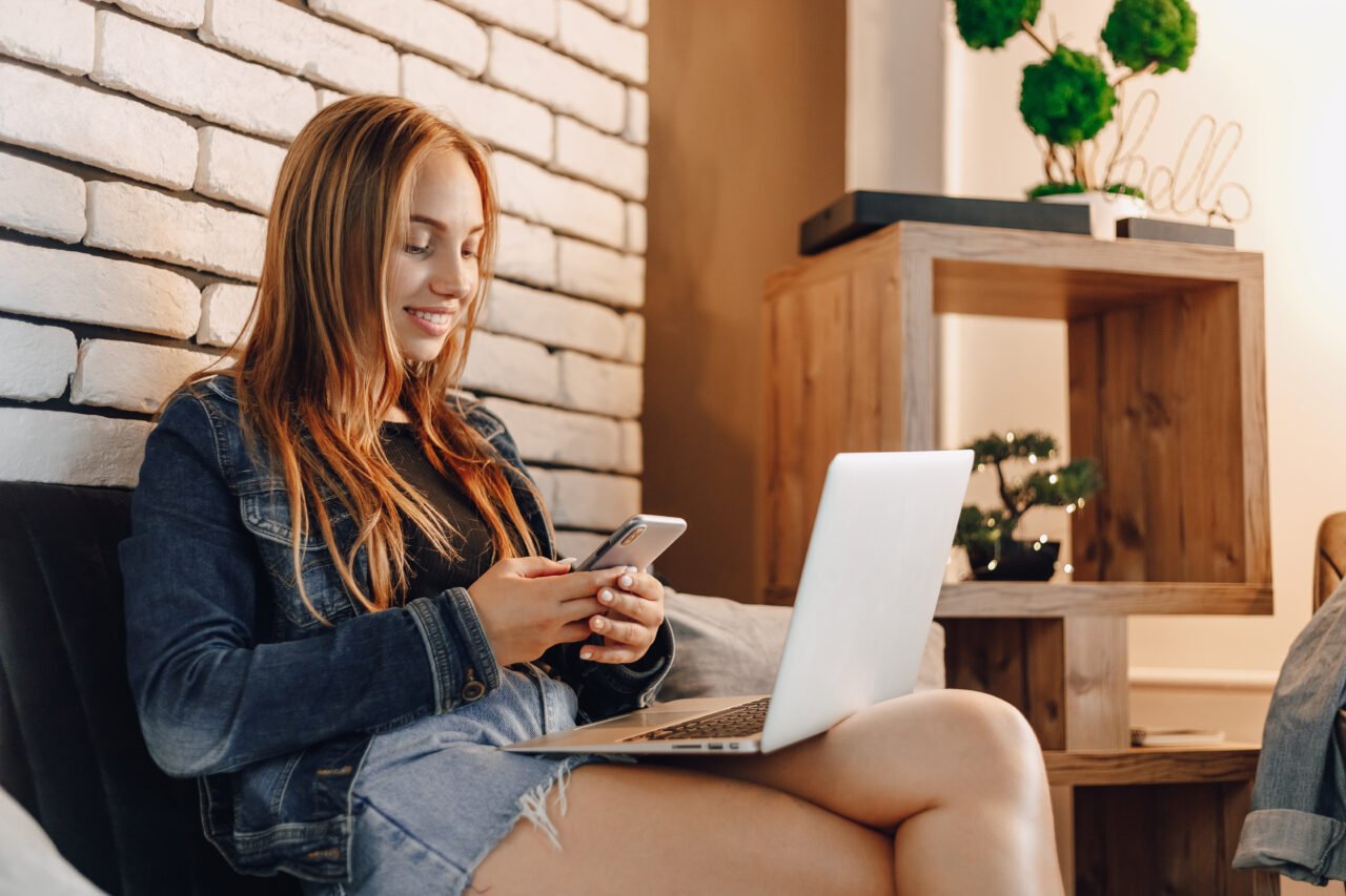 attractive girls in electronics store in lounge area on sofa with laptops and phones.