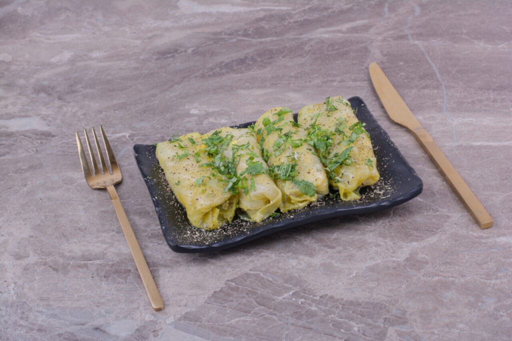 Caucasian cabbage wraps with minced herbs in a black ceramic platter