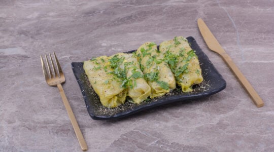 Caucasian cabbage wraps with minced herbs in a black ceramic platter