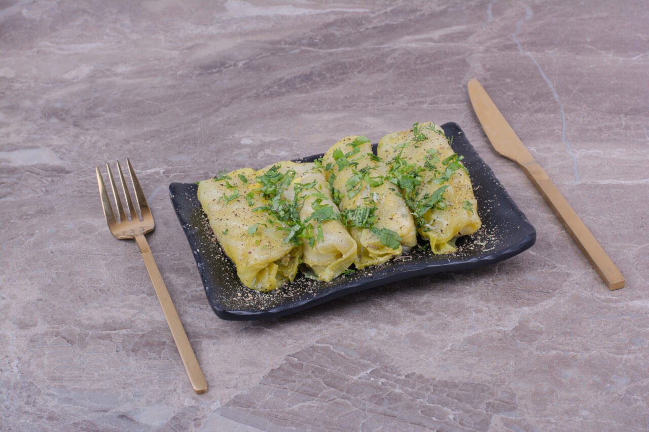 Caucasian cabbage wraps with minced herbs in a black ceramic platter