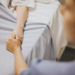 Nurse holding her patients hand